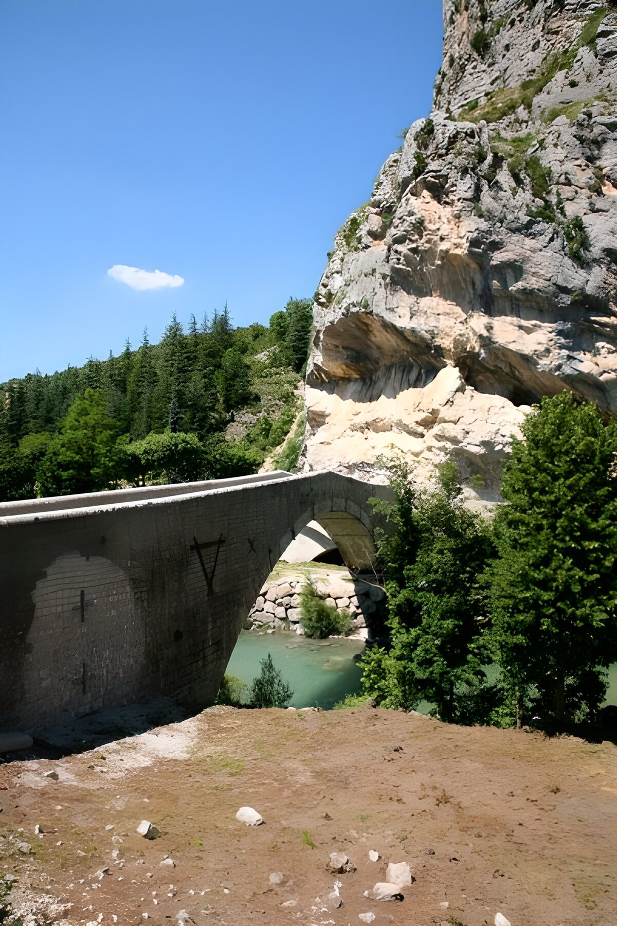 Arch bridge over a sunlit turquoise river