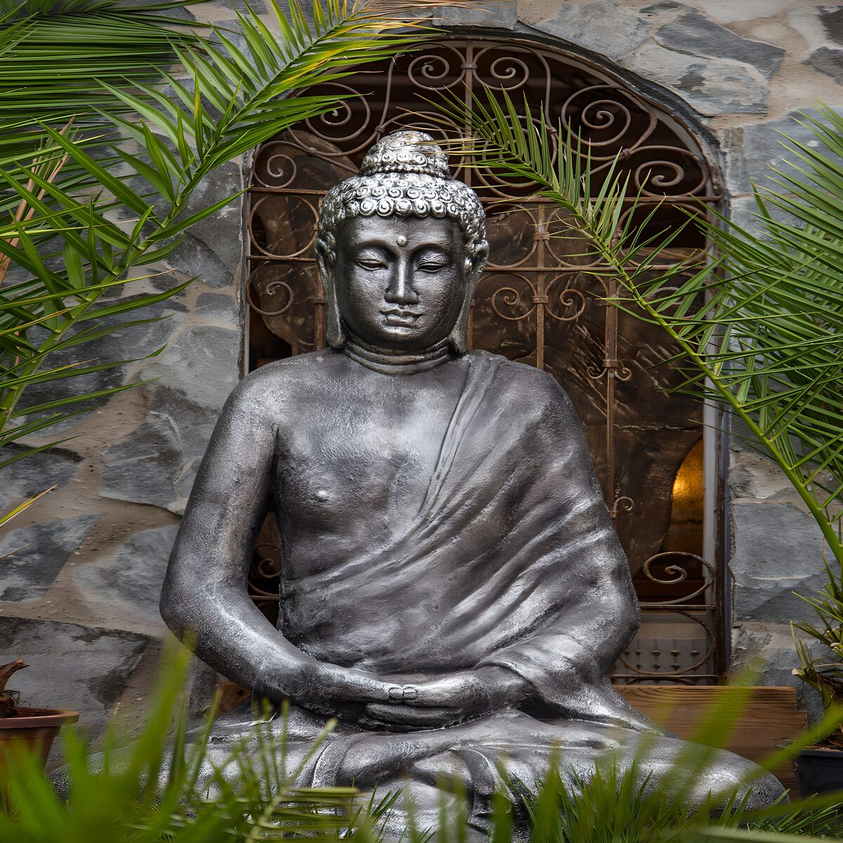 Grey Buddha at rest among palms