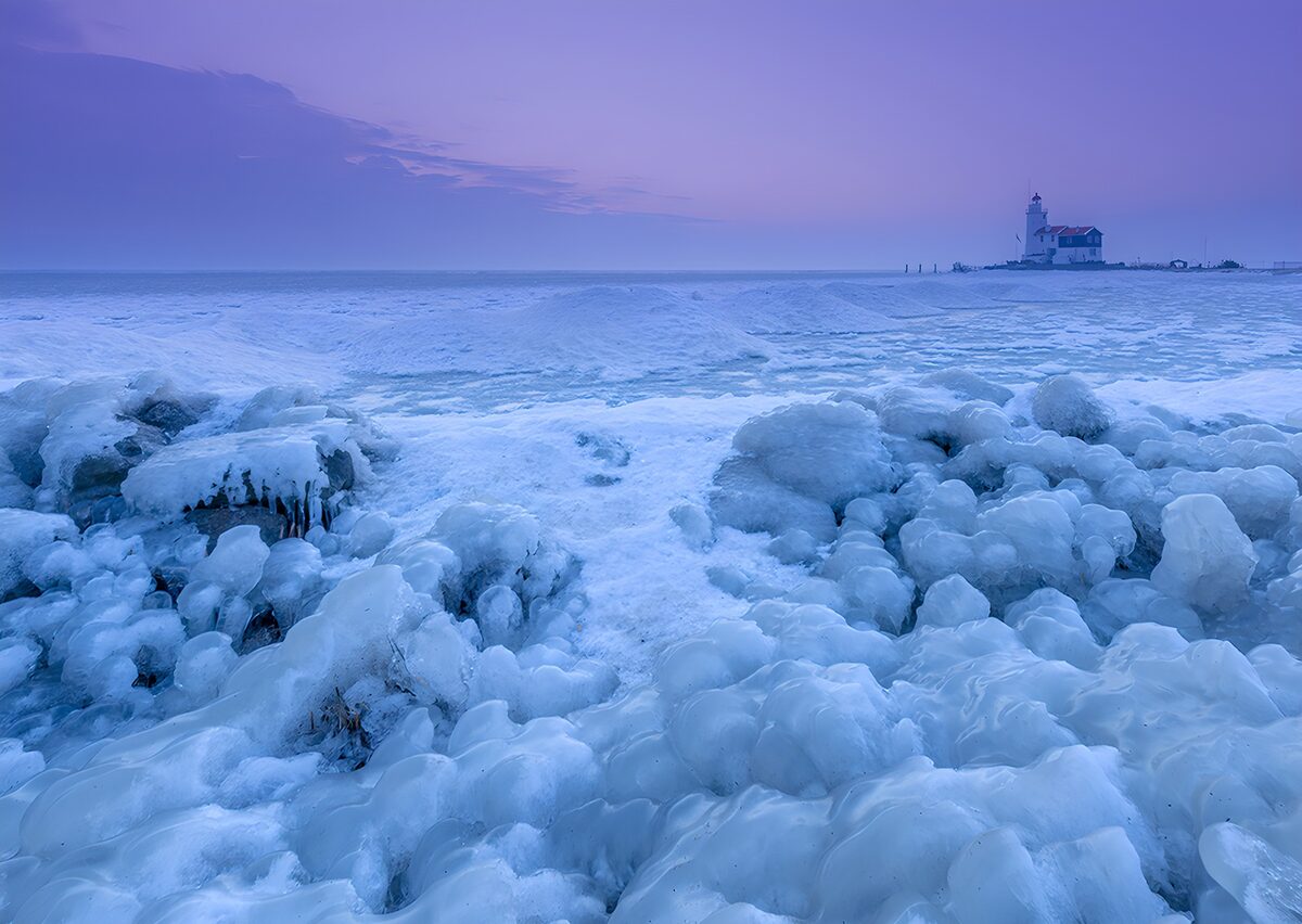 Ice-covered rocks and a distant lighthouse