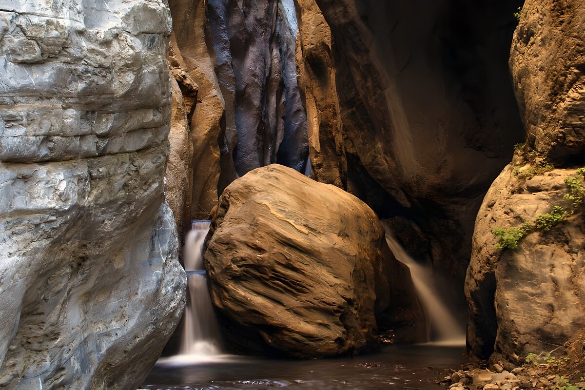 Waterfalls beside a wedged boulder