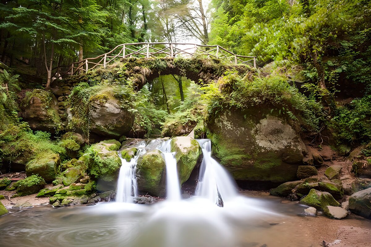 Woodland waterfall beneath a stone bridge