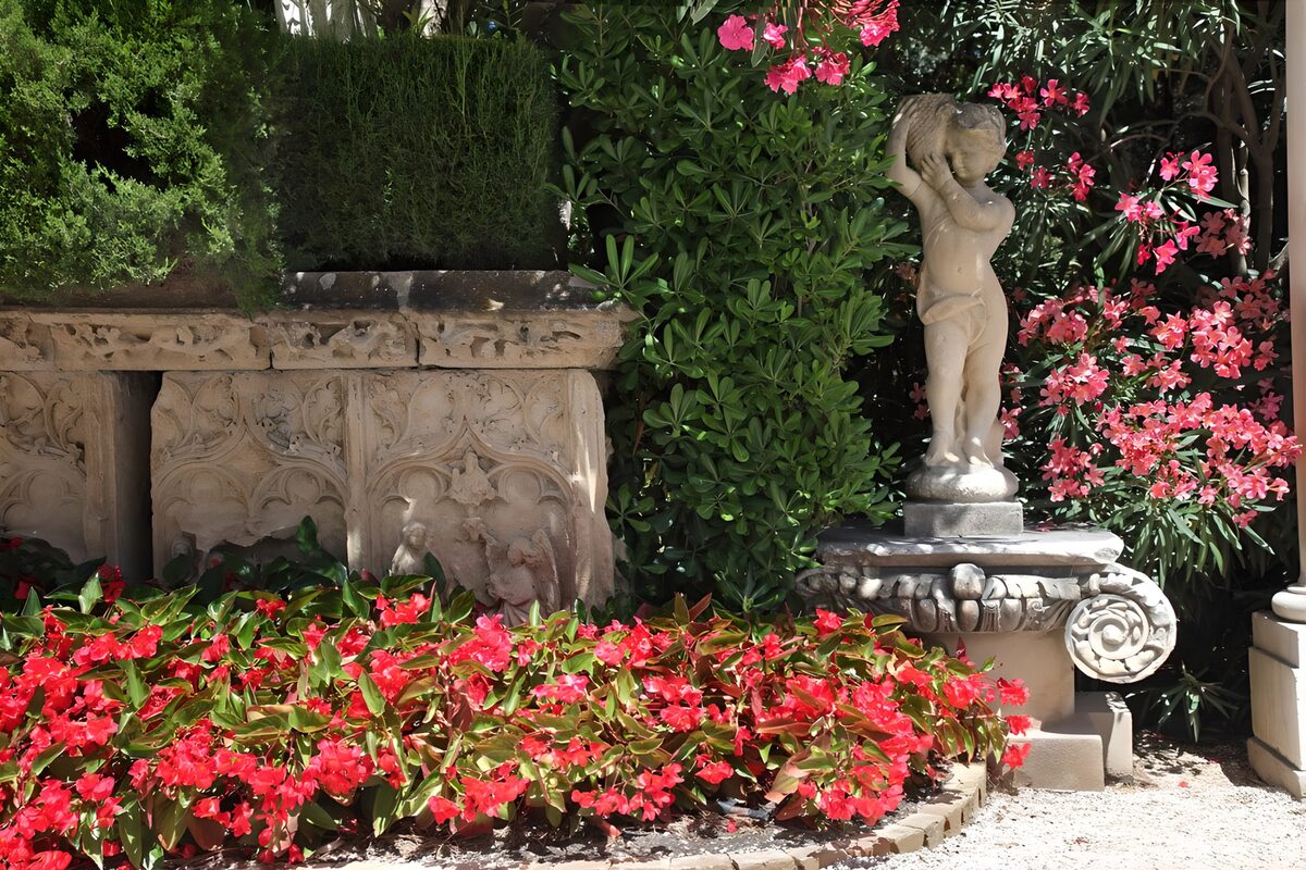 Child statue among sunlit garden flowers