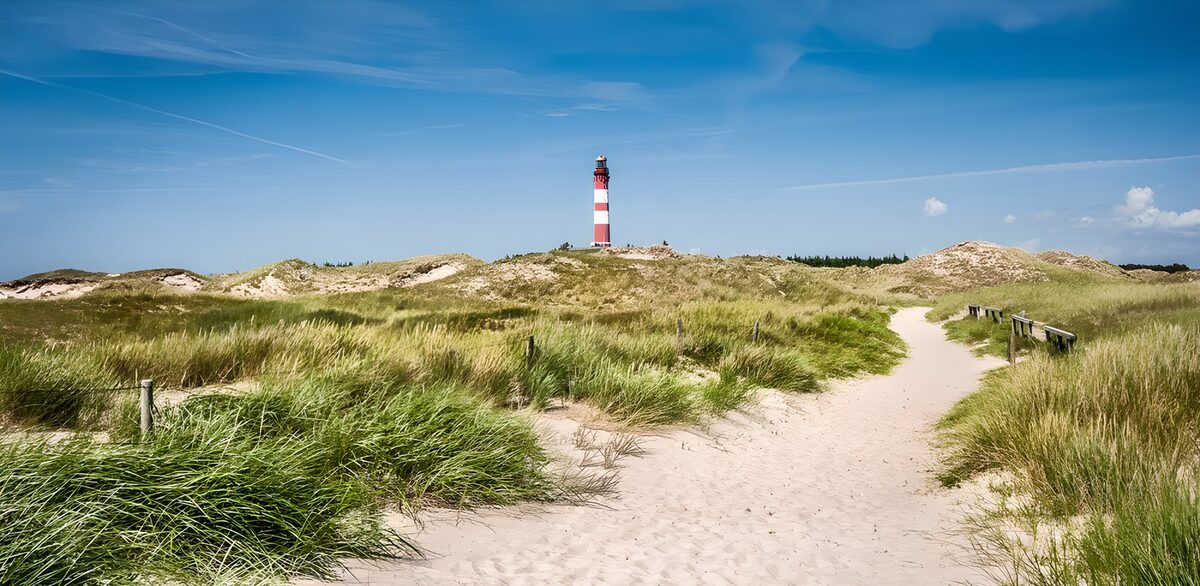 Sunlit path to a striped lighthouse