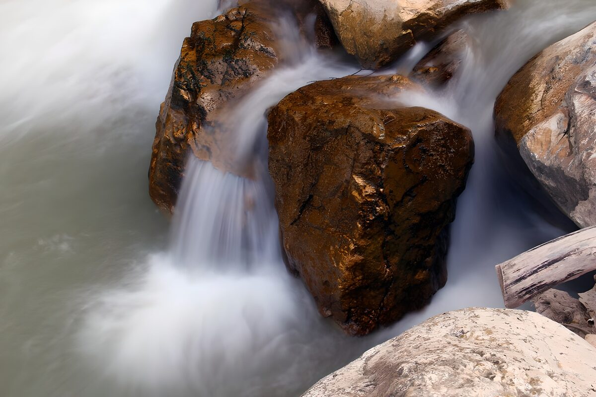 Silky cascades between warm brown boulders