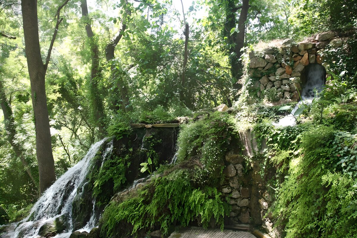 Waterfall and stone wall in woodland shade