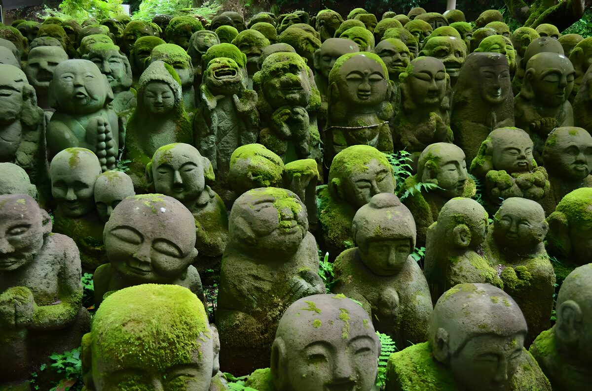 Moss-covered Buddhist statues in the shade