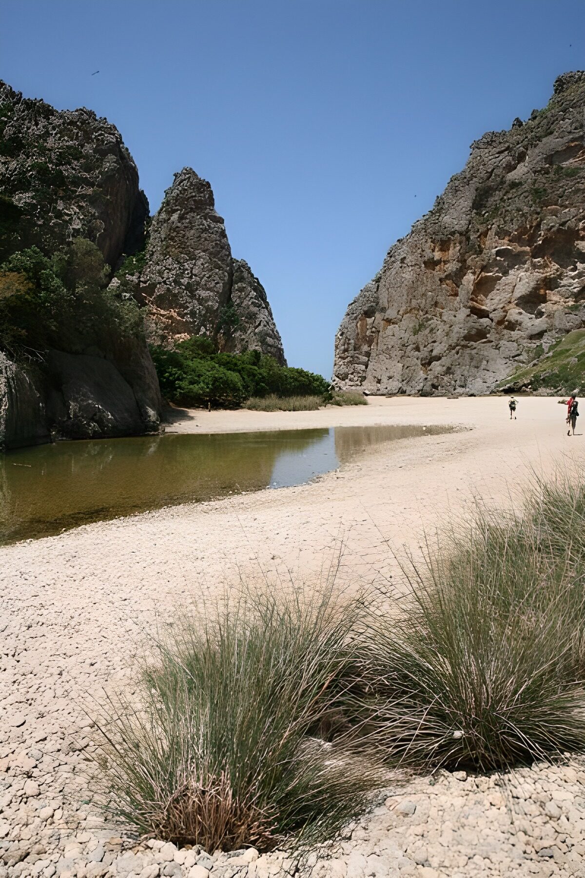 Sunlit cliffs above a quiet sandy passage