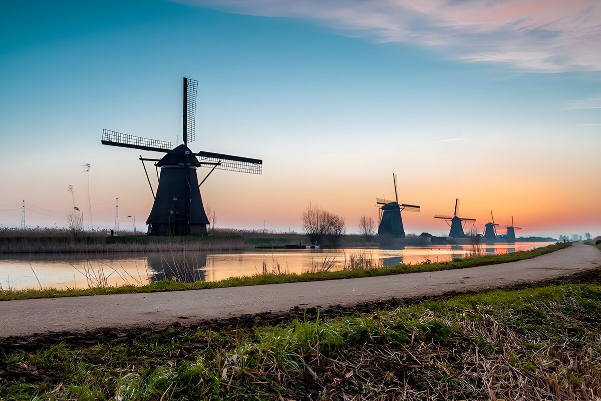 Five windmills beside a canal at sunset