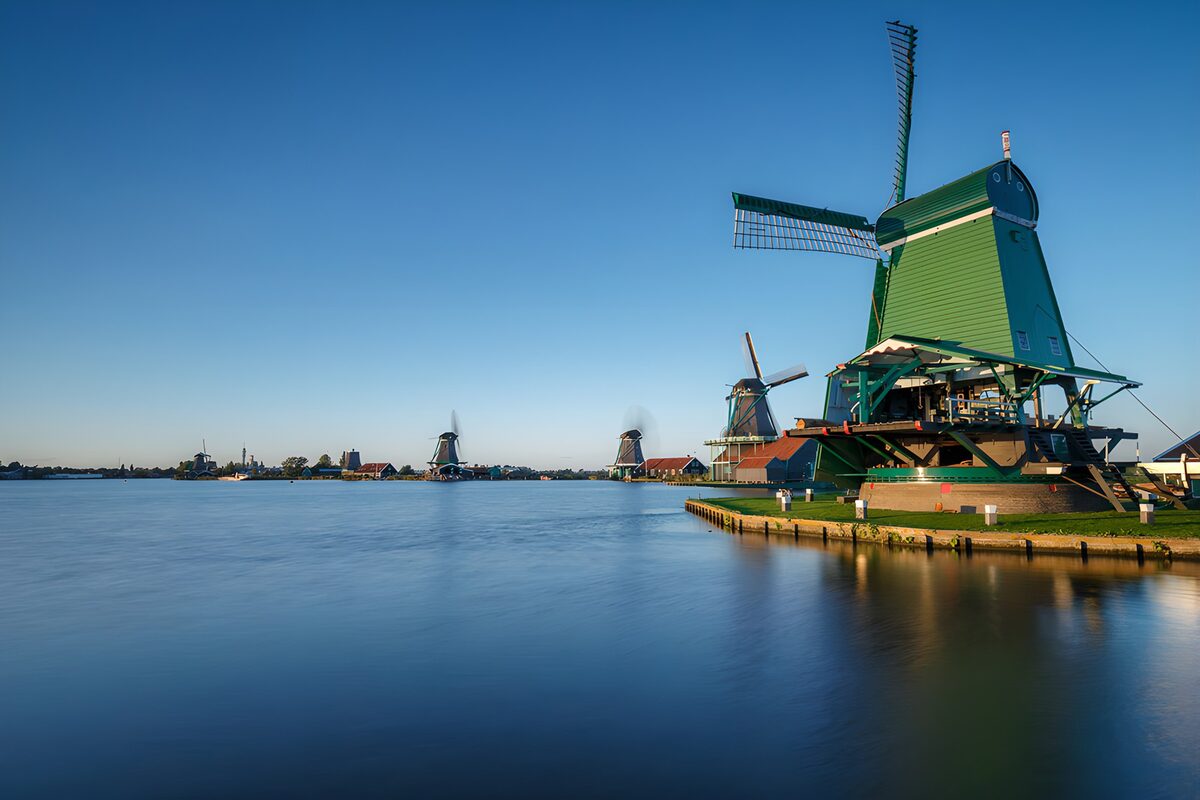 Green windmill beside blue water