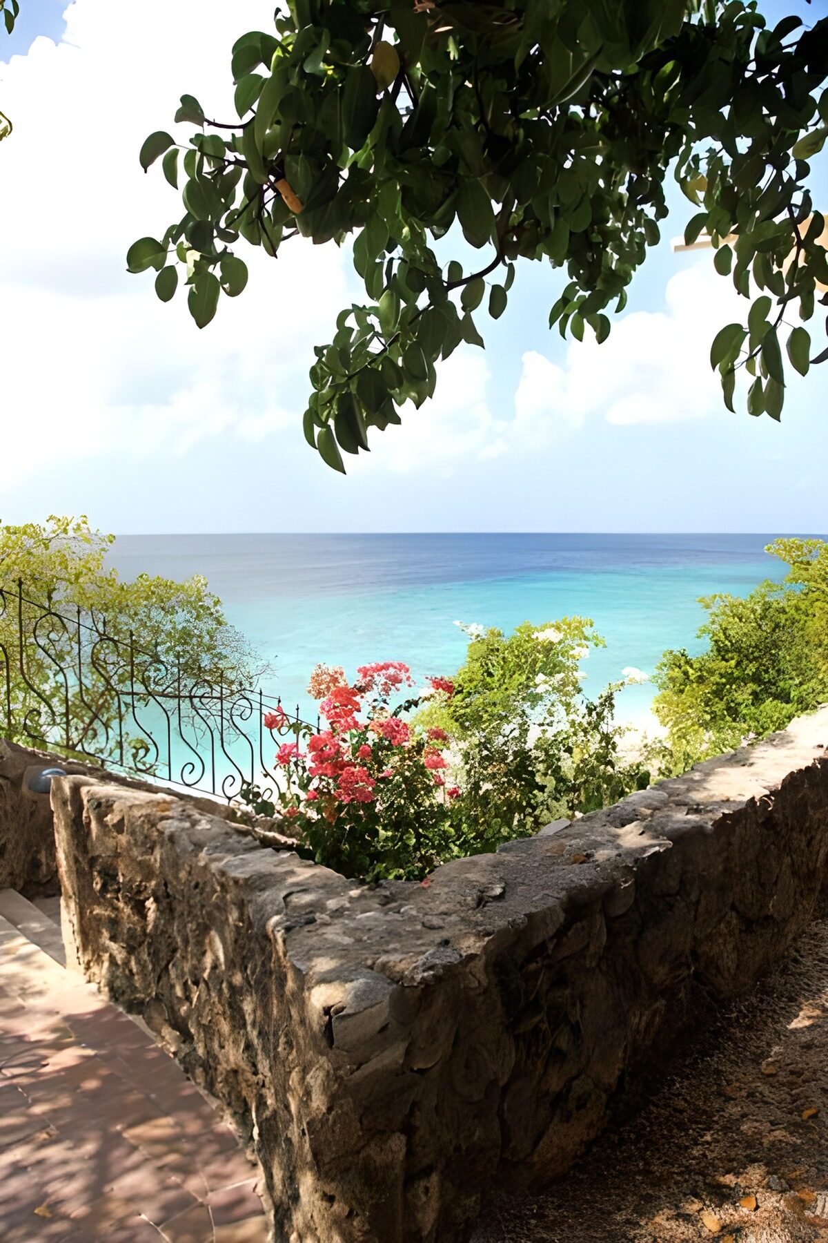 Sunlit sea beyond a flower-filled garden