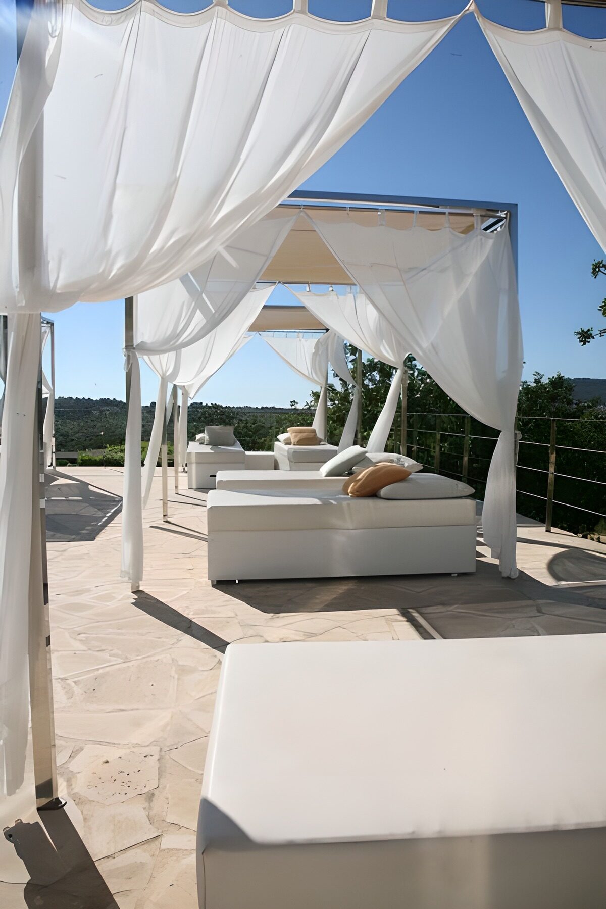 White daybeds beneath sunlit canopies