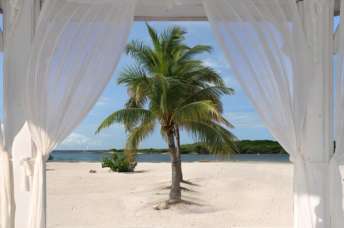 Sunlit beach through white curtains