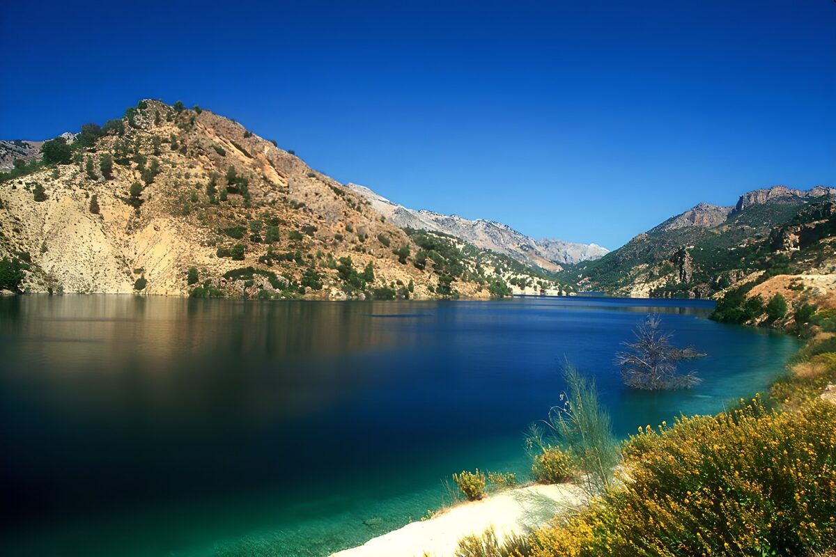 Blue lake beneath sunlit mountains