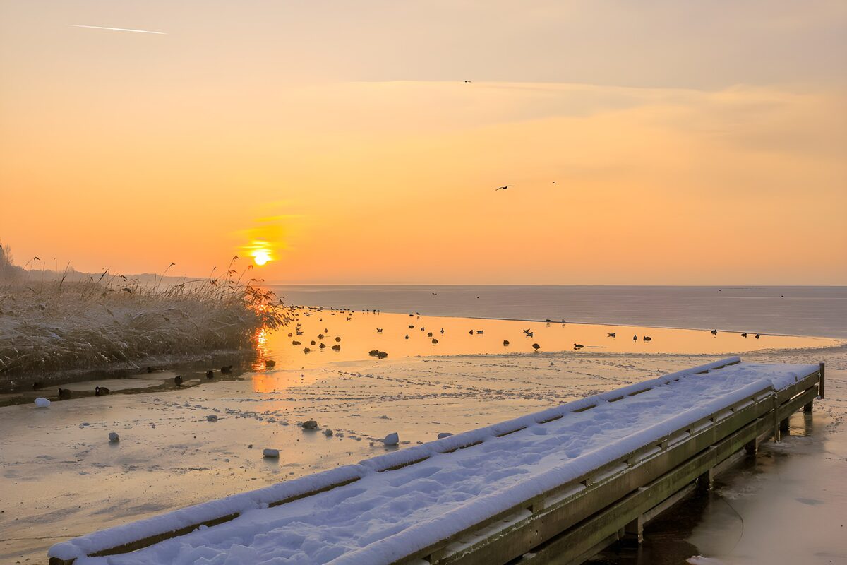 Snow-covered jetty at sunset