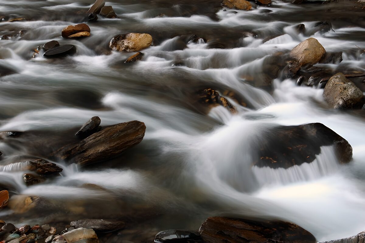 Silky water over dark stream rocks