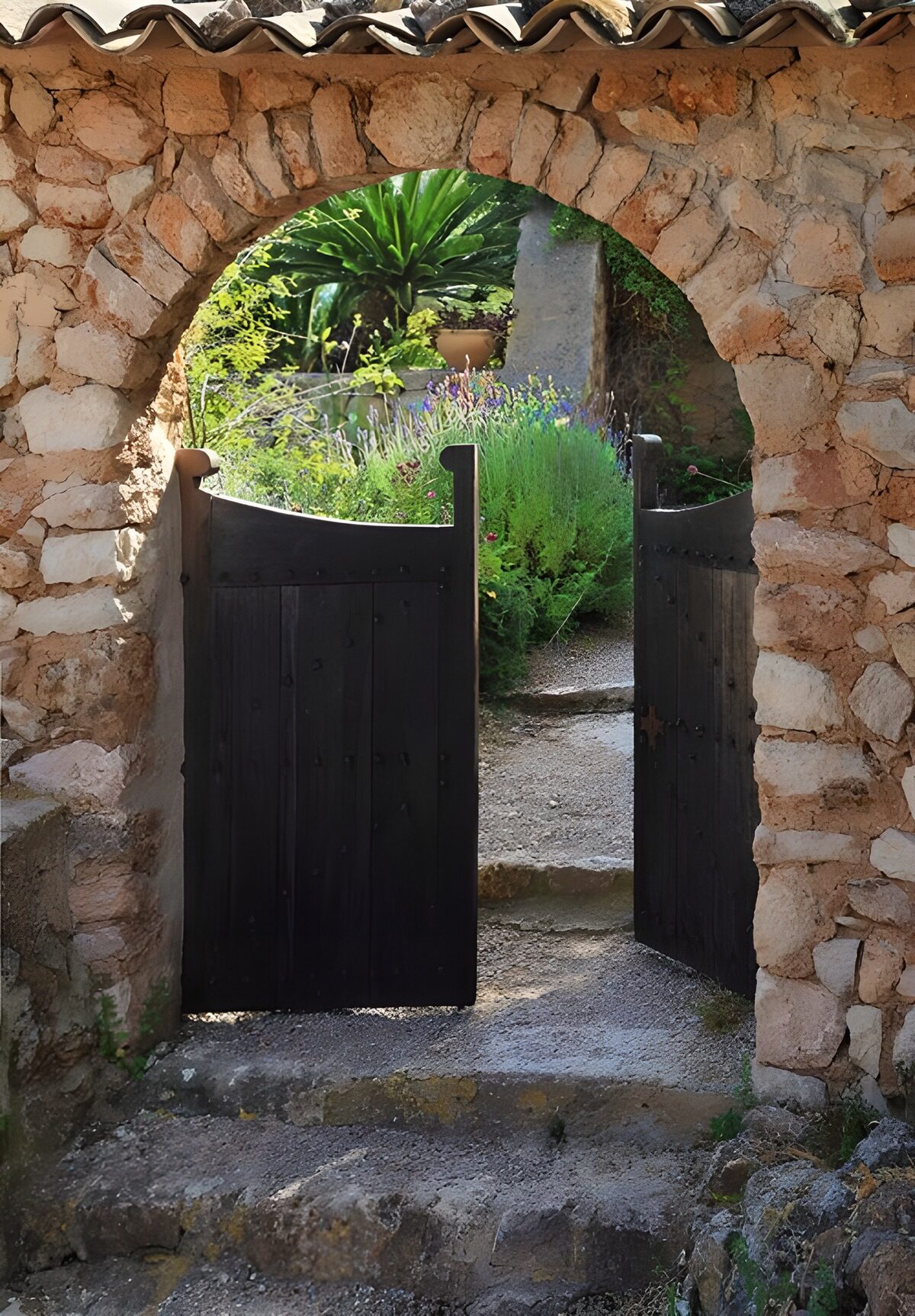 Open wooden gate beneath a stone arch