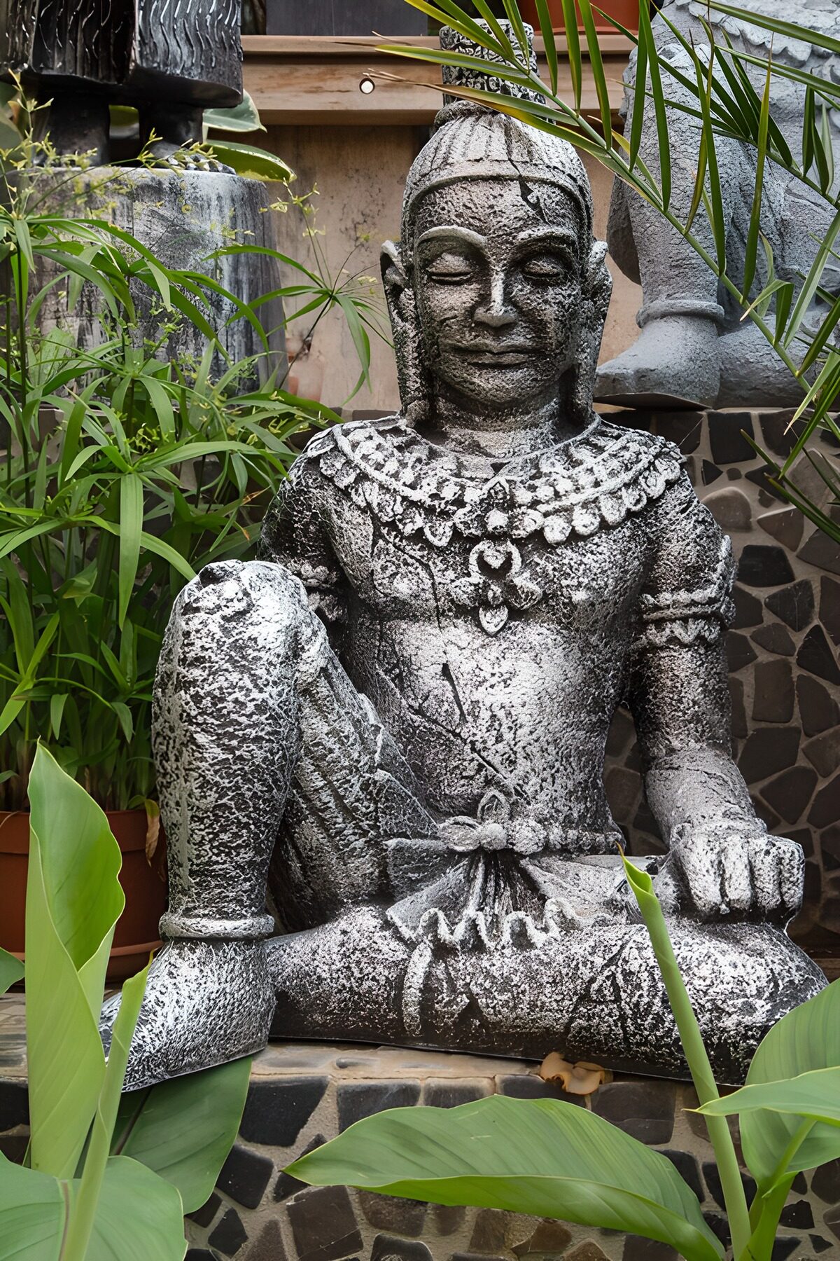 Weathered stone statue among lush leaves