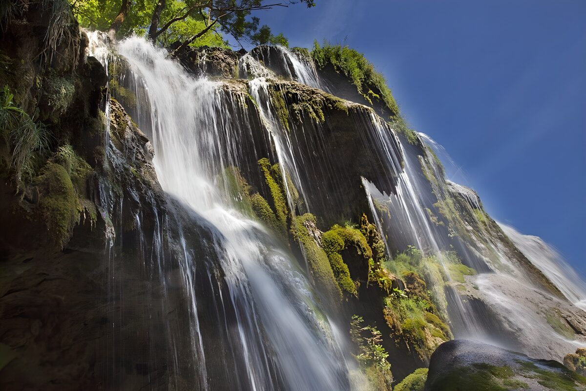 Sunlit waterfall over mossy rock