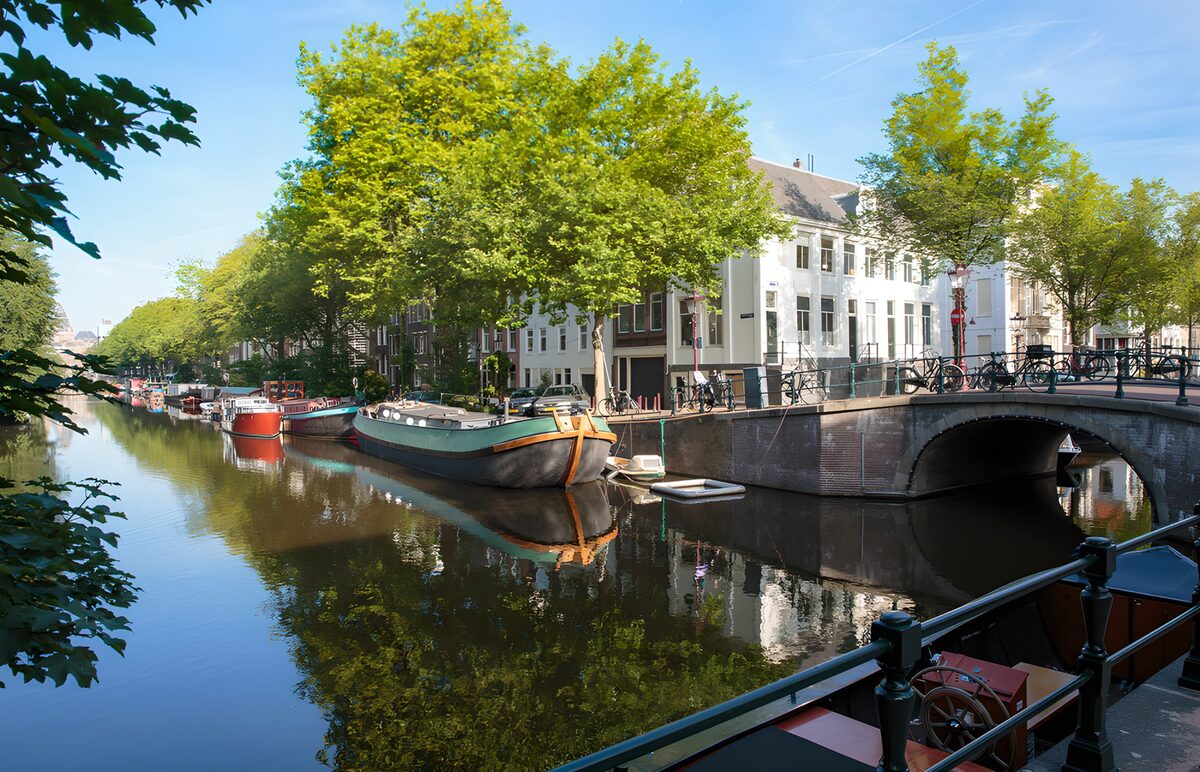 Sunlit canal with boats and a brick bridge