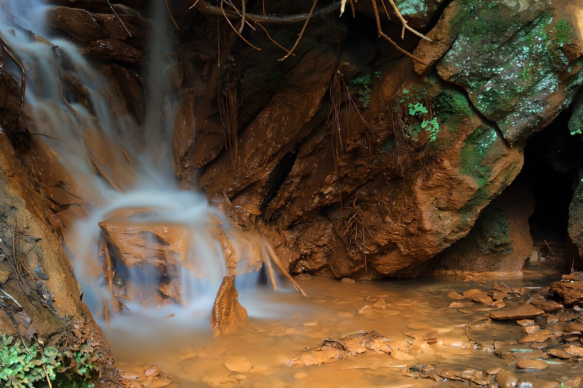 Small waterfall over warm, rusty-brown rocks