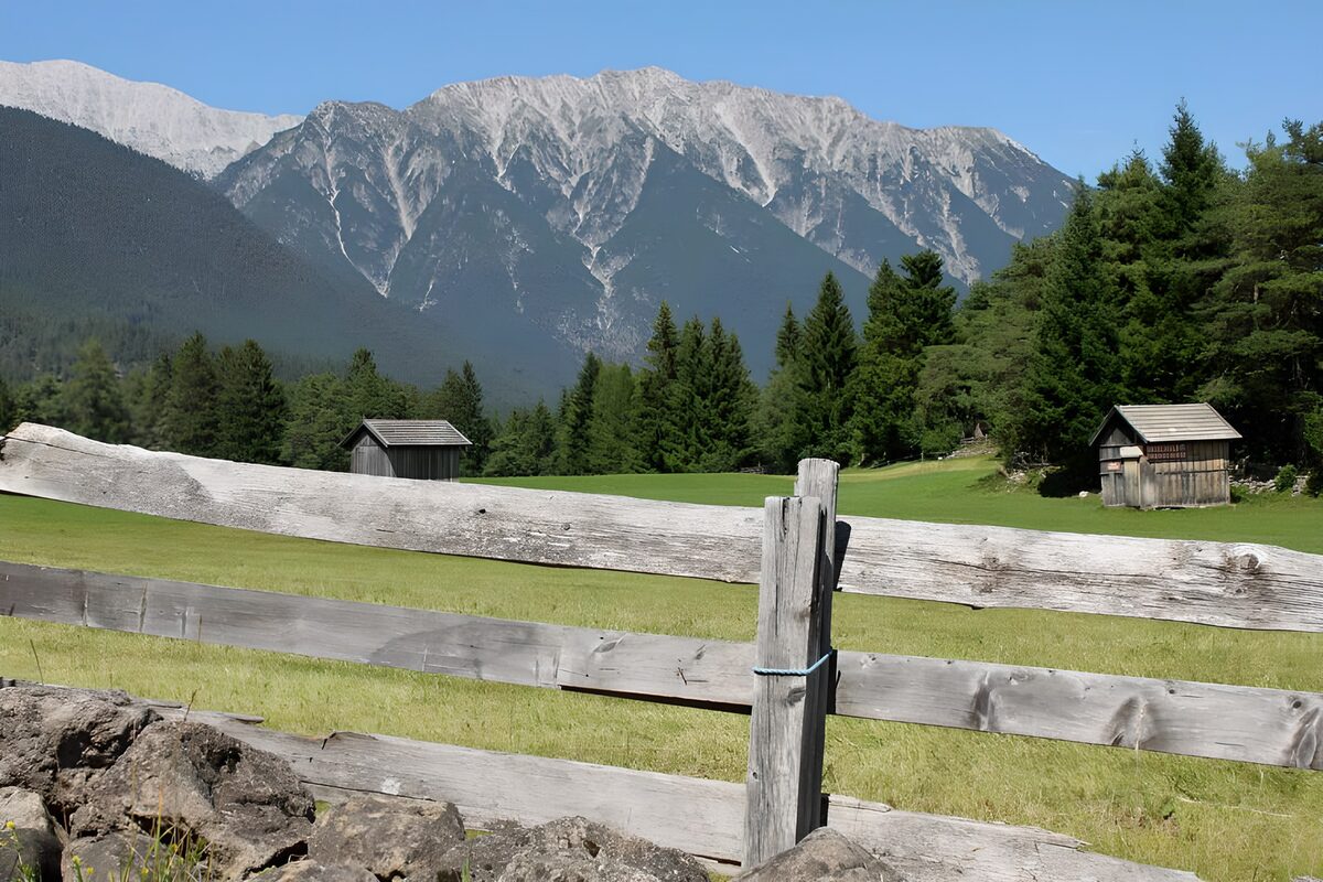 Mountain meadow with sheds and a wooden fence