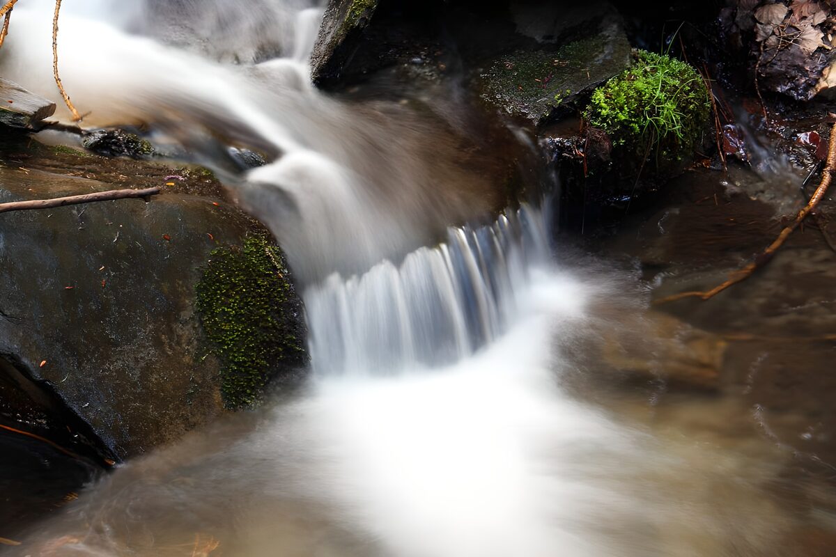 Small cascade over dark, mossy rocks