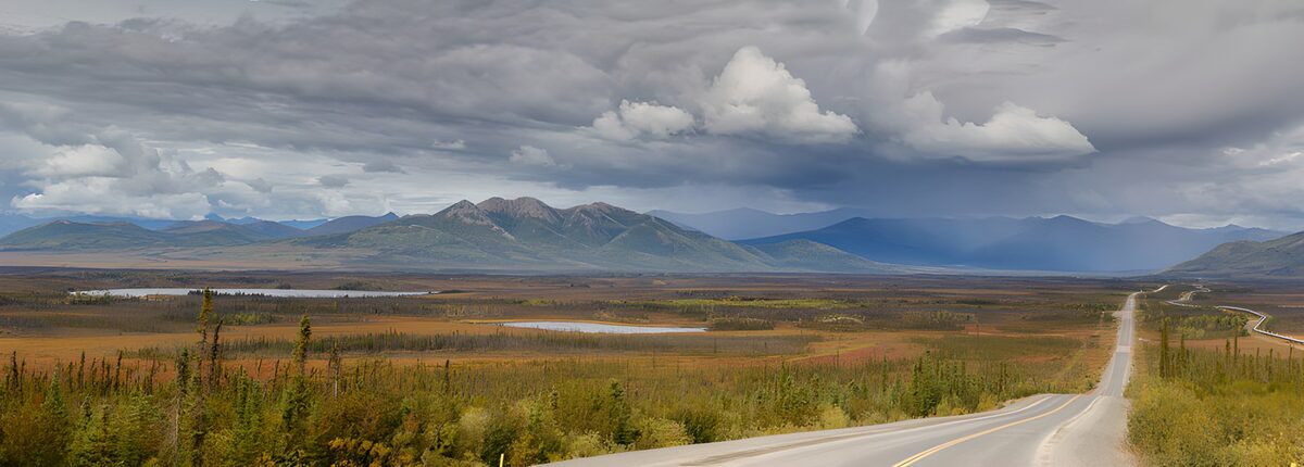 Valley road beneath stormy mountain skies