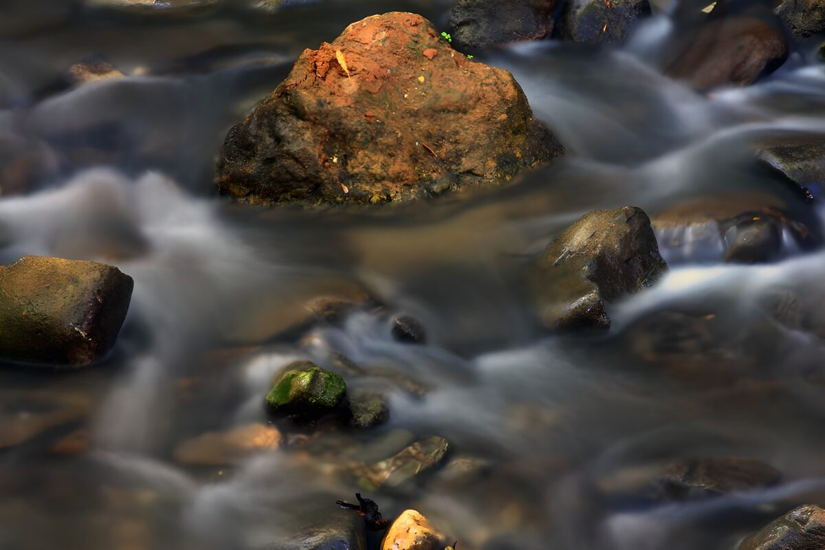 Rust-coloured boulder in a flowing stream