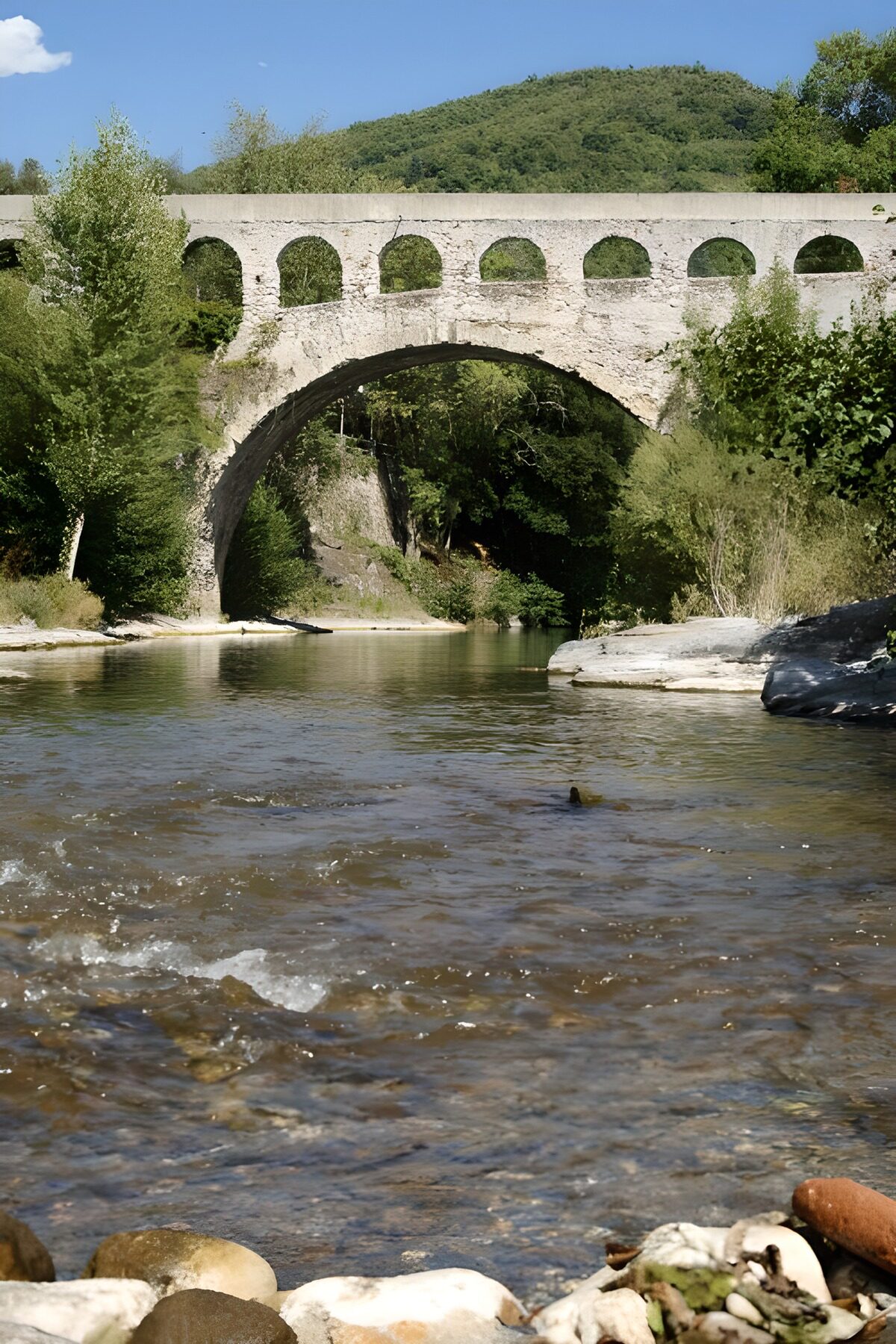 Old stone bridge over sunlit shallows