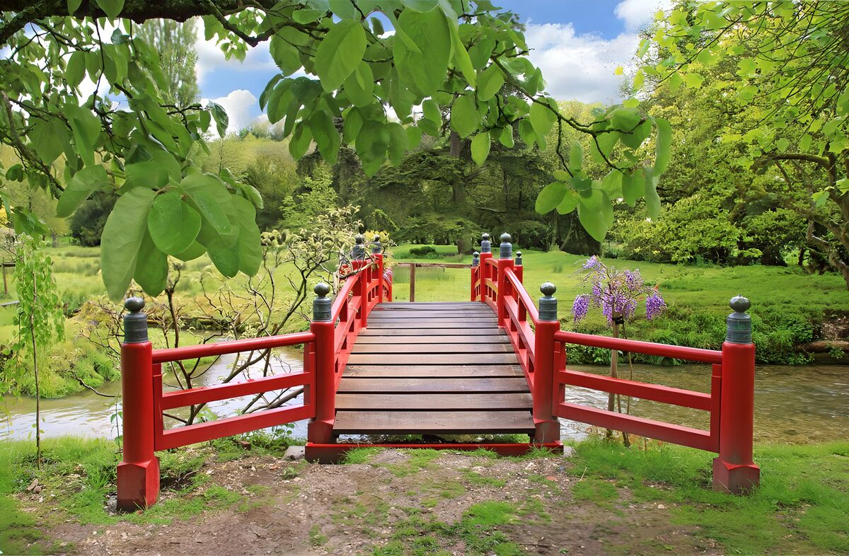 Red wooden bridge in a leafy garden