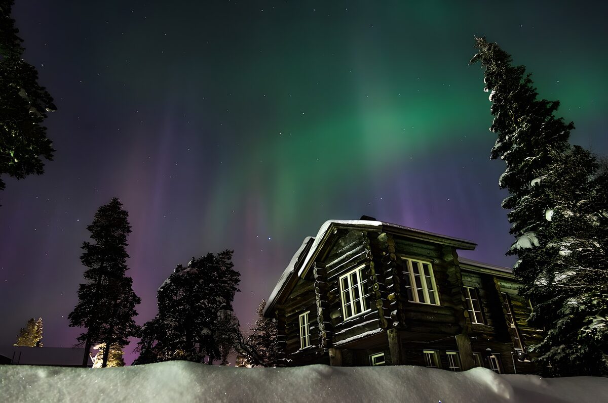 Snowy log house beneath the northern lights