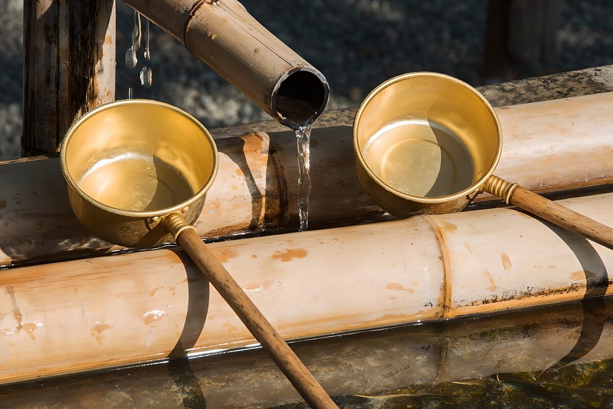 Sunlit ladles beneath a bamboo spout