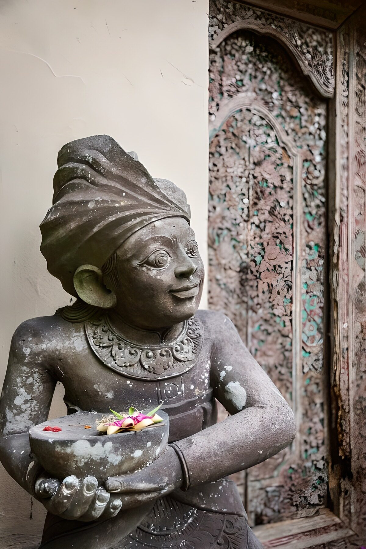 Weathered statue with a quiet flower offering