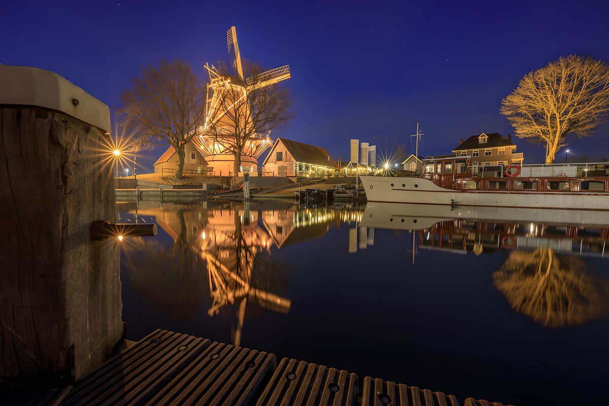 Windmill and boat in the harbour at night
