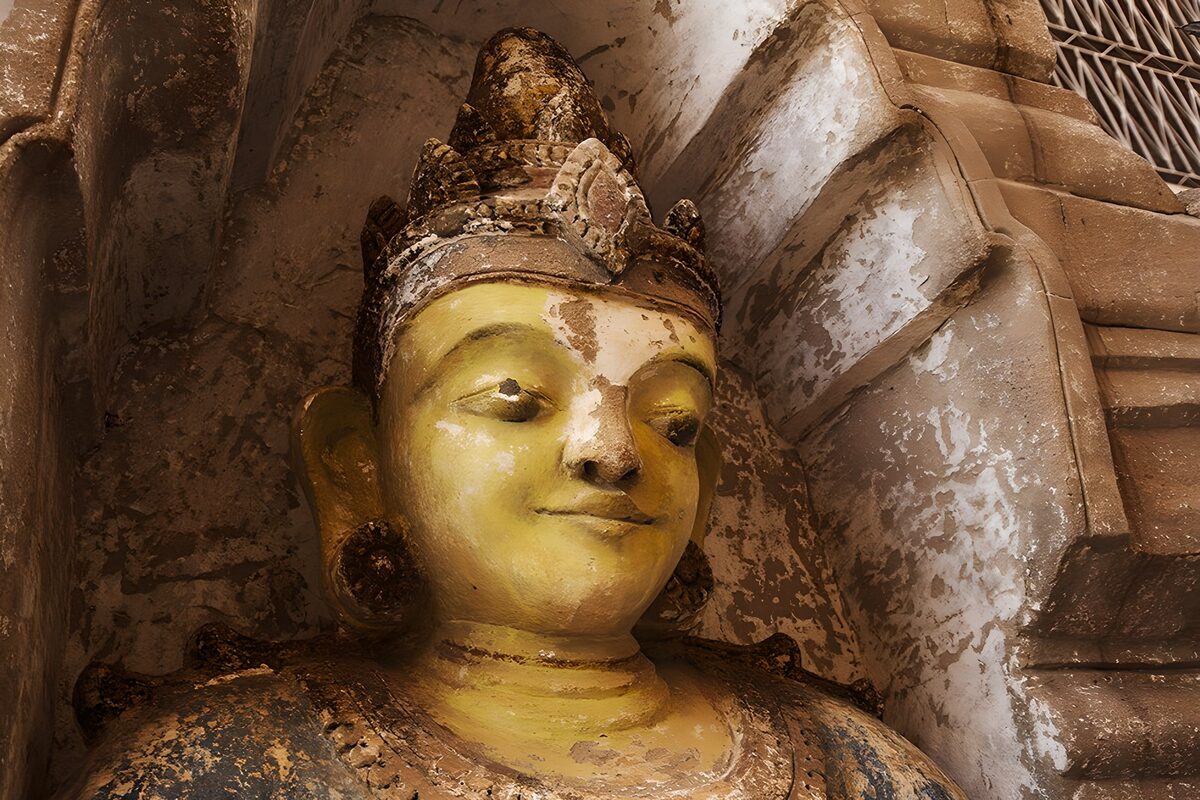 Weathered golden Buddha in a niche