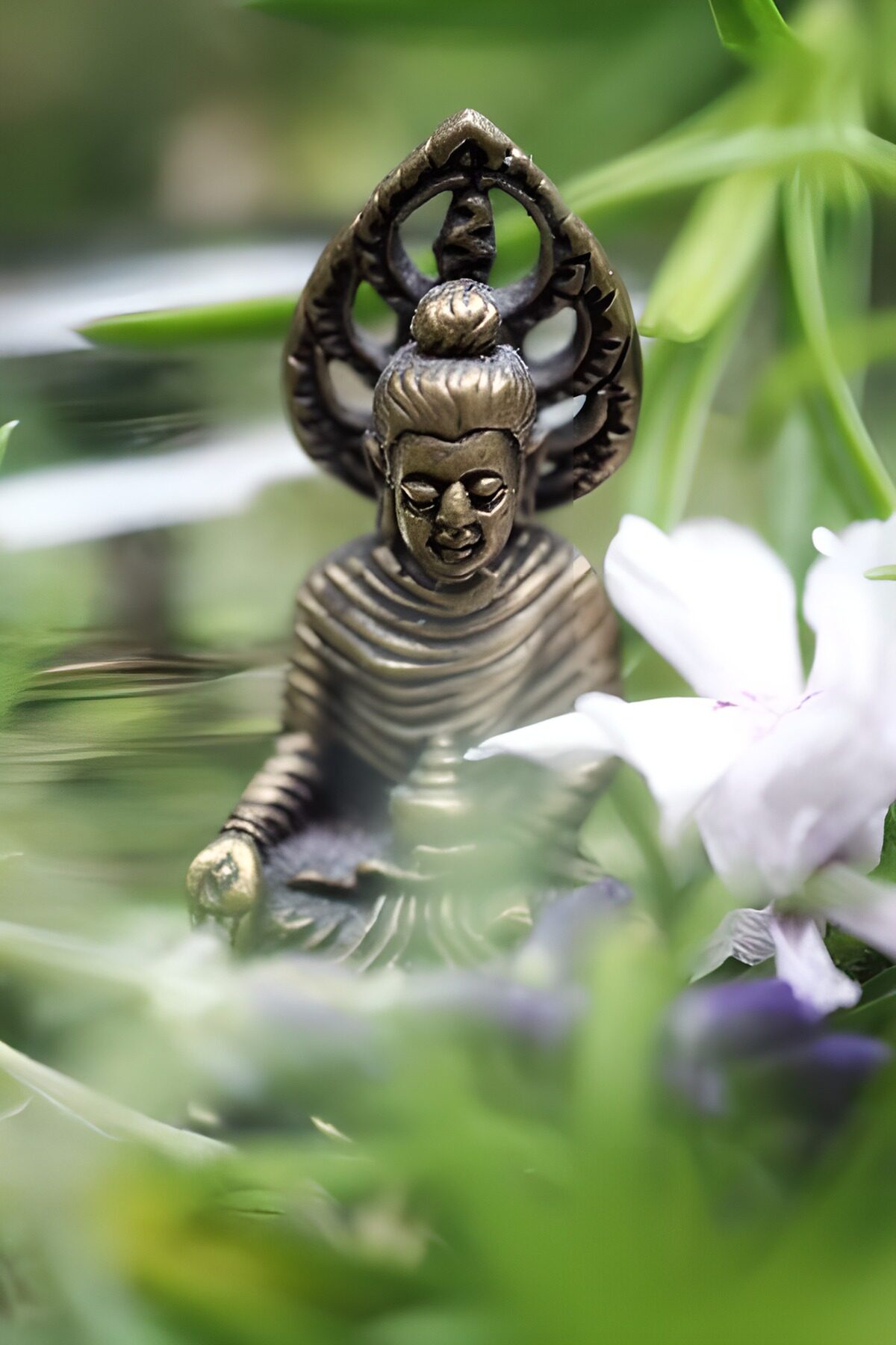 Bronze Buddha beside a pale bloom