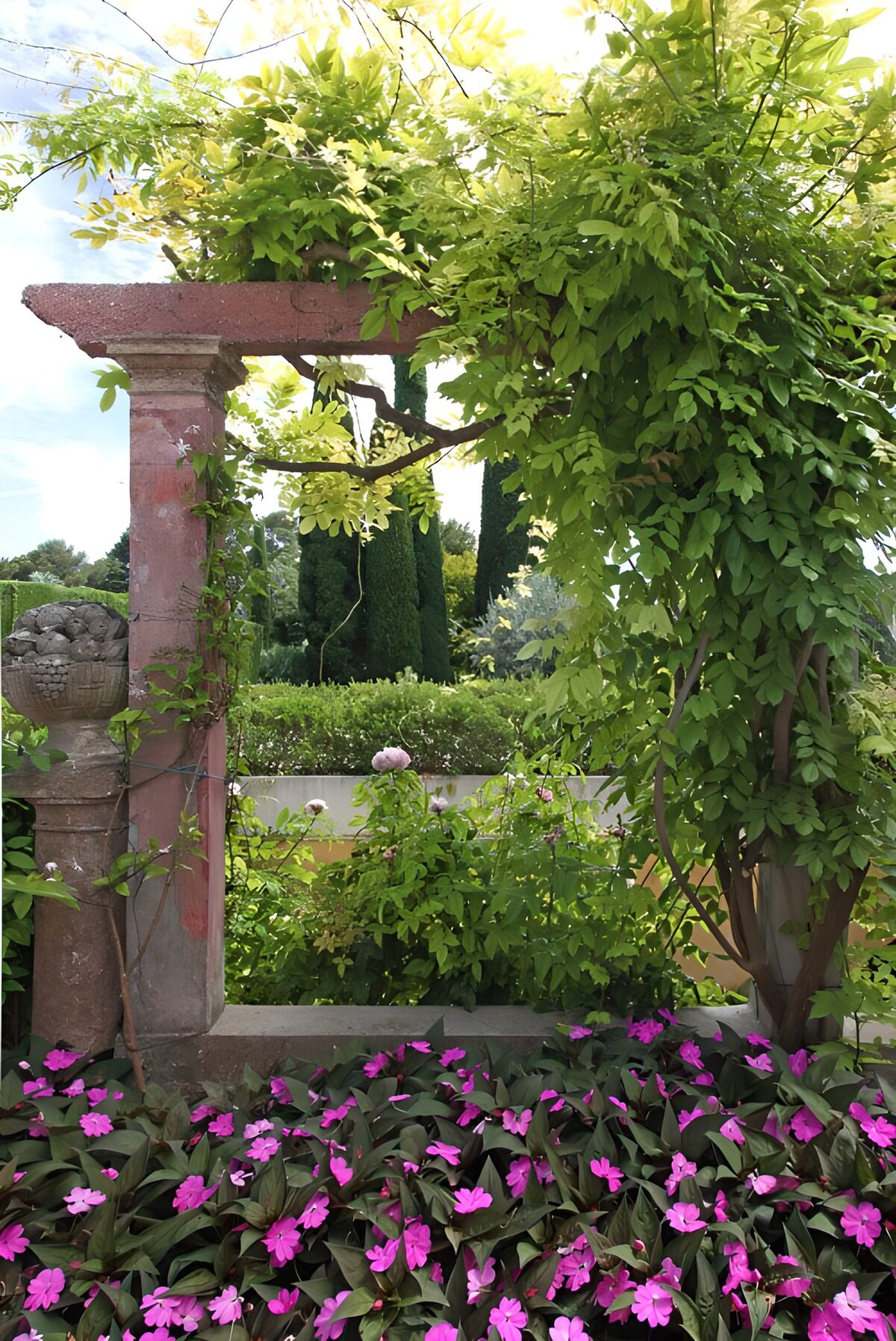 Sunlit stone pergola with pink flowers