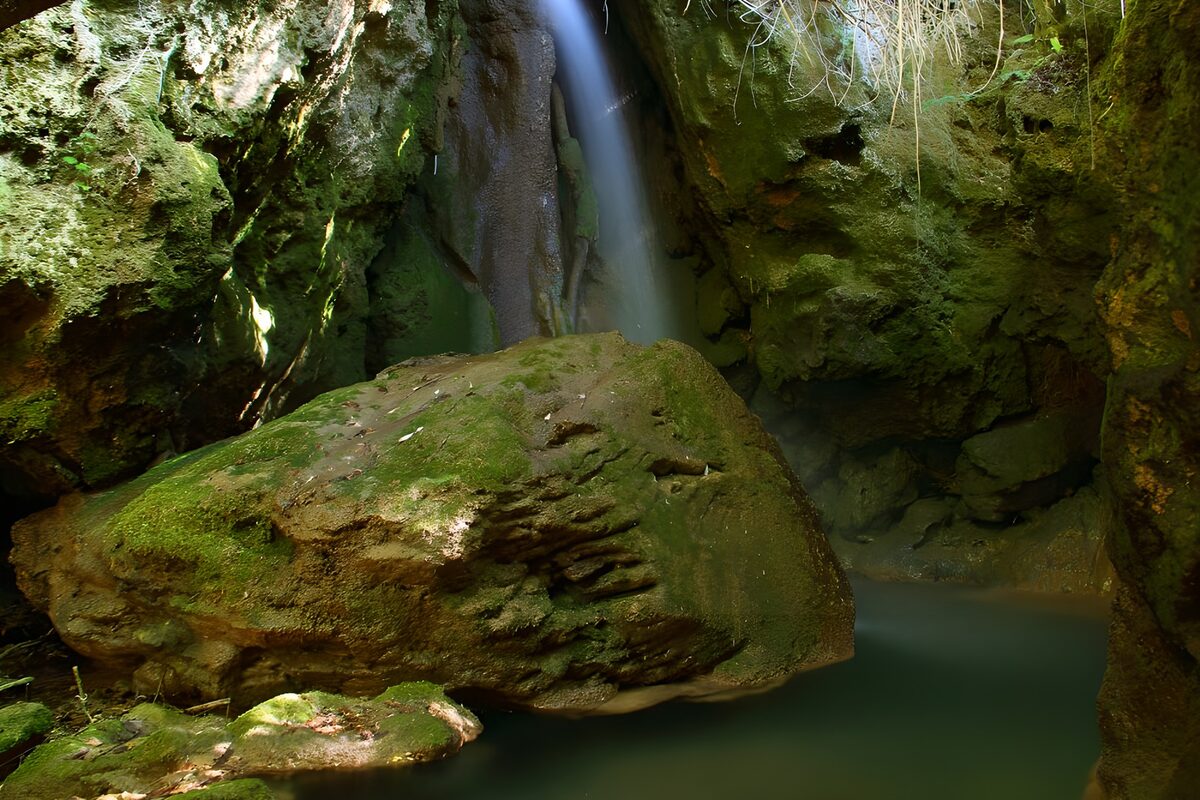 Waterfall and mossy rocks in the shade